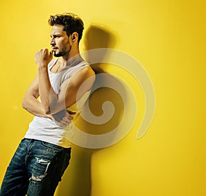 Handsome man leaning on the bright, yellow wall