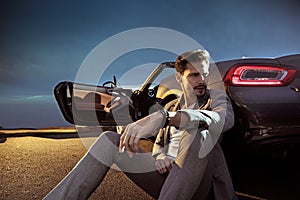 Handsome man leaning on the luxurious car
