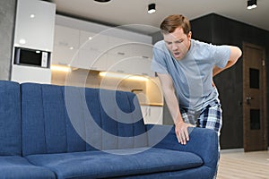 Handsome man lifting sofa and feeling pain. man droped sofa because of painful back