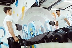 Handsome man lifting weights in gym