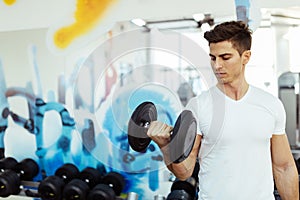 Handsome man lifting weights in gym