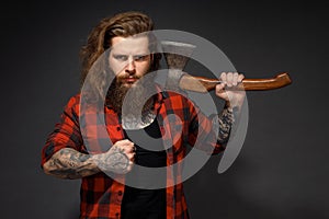 Handsome man with long hair with an ax in his hands on a dark studio background