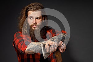 Handsome man with long hair with an ax in his hands on a dark studio background