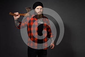 Handsome man with long hair with an ax in his hands on a dark studio background