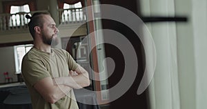 Handsome man looking out the window with crossed hands in a lobby