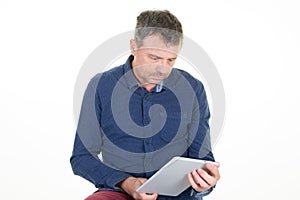 Handsome man is looking while reading his digital touchscreen tablet computer