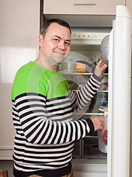 Handsome man looking for something in refrigerator