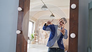 A handsome man looks in the mirror. A side view of a young man in a mirror in a modern bedroom