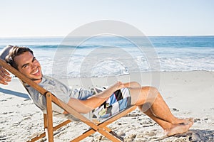 Handsome man lying on his deck chair smiling at camera