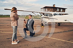 Handsome man making proposal to his girlfriend at airdrome