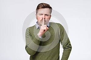 Handsome man making silence gesture asking you to keep secret.