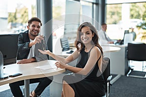 Handsome man manager giving car keys after holding successful deal to his beautiful woman client at dealership office