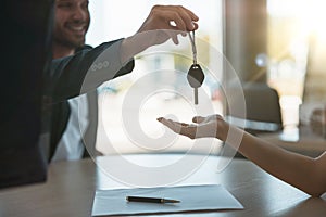 Handsome man manager giving car keys after holding successful deal to his client at dealership office