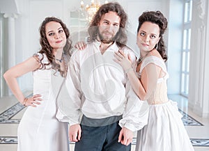 Handsome man in medieval costume and two woman in old-fashioned