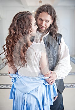 Handsome man in medieval costume undress beautiful woman photo