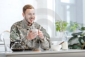 Handsome man in military uniform smiling and drinking coffee