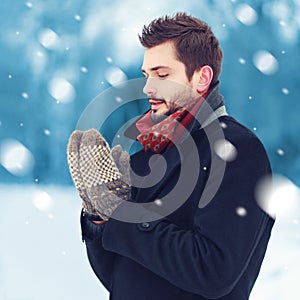 Handsome man in mittens freezes outdoors in winter day