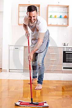 Handsome man mopping floor at home