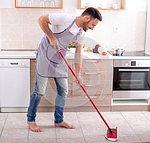 Handsome man mopping kitchen floor