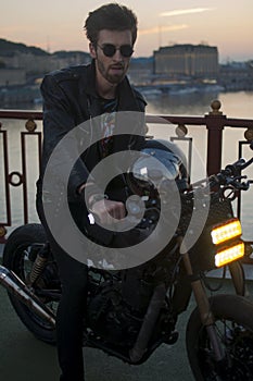 handsome man on a motorcycle against the background of the sunset in the city