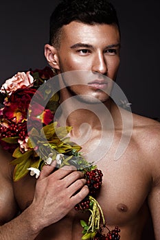 A handsome man with a naked torso, bronze tan and flowers on his body.