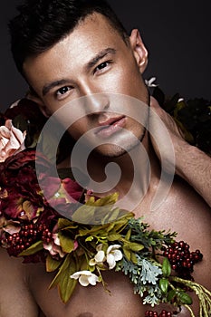 A handsome man with a naked torso, bronze tan and flowers on his body.