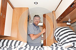 Handsome man open wooden door in camper van motor home during vanlife vacation in  RV