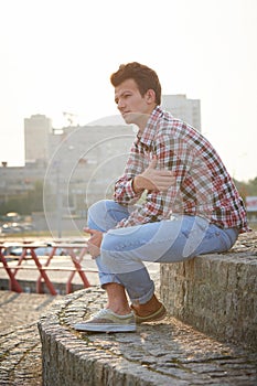 Handsome man outdoors sitting on stone stairs