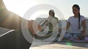 Handsome man play didgeridoo while woman practice meditation at rooftop.