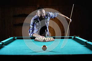 Handsome man playing billiards alone