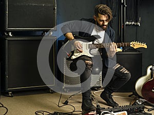 Handsome man playing an electric guitar in a studio