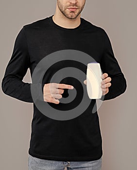 handsome man point finger on bottle of unbranded cosmetic. man hold unbranded cosmetics