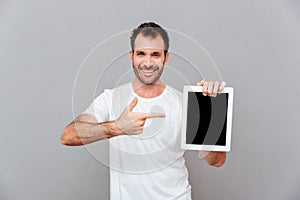 Handsome man pointing finger on blank tablet computer screen