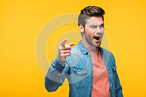 Handsome man pointing with finger Isolated On yellow