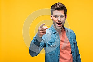 Handsome man pointing with finger Isolated On yellow