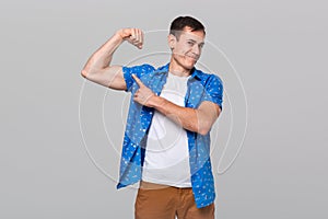 Handsome man pointing at his muscle bicep.