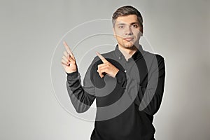 Handsome man pointing at something on grey background