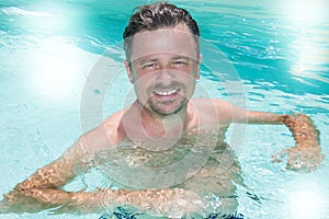 Handsome man in the pool enjoys the relaxation