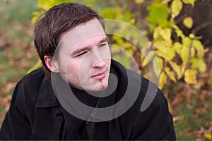 Handsome man portrait in autumn leaves background