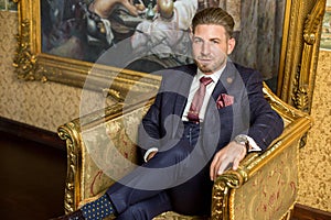 Handsome man posing on armchair in luxury hotel