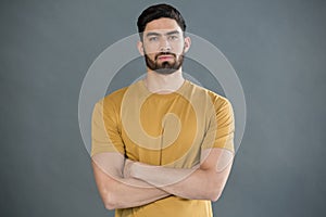 Handsome man posing with arms crossed against grey background