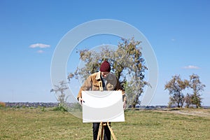 Young artist painting an autumn landscape on the nature background. Art concept.