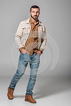 handsome man posing in corduroy shirt and autumn jacket with hands in pockets of jeans