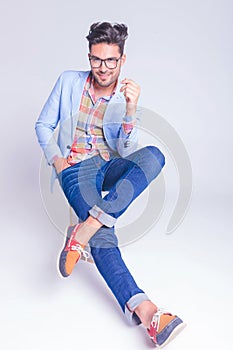 Handsome man posing seated with legs crossed