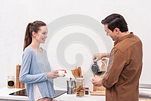 handsome man pouring coffee for wife and himself