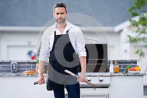 Handsome man preparing barbecue. Male cook cooking meat on barbecue grill. Guy cooking meat on barbecue for summer