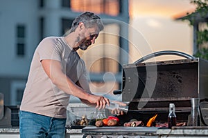 Handsome man preparing barbecue. Male cook cooking meat on barbecue grill. Guy cooking meat on barbecue for summer