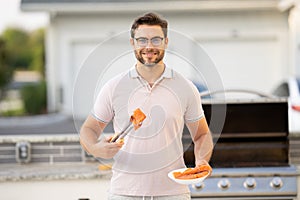 Handsome man preparing barbecue. Male cook cooking salmon fish on barbecue grill. Guy cooking salmon fish on barbecue