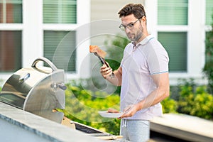 Handsome man preparing barbecue salmon. Male cook cooking meat on barbecue grill. Guy cooking salmon on barbecue for