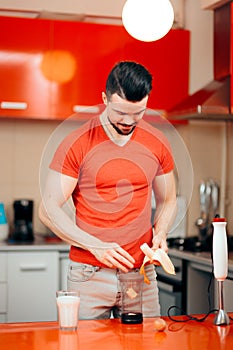 Handsome Man Preparing Protein Shake with Raw Eggs and Banana